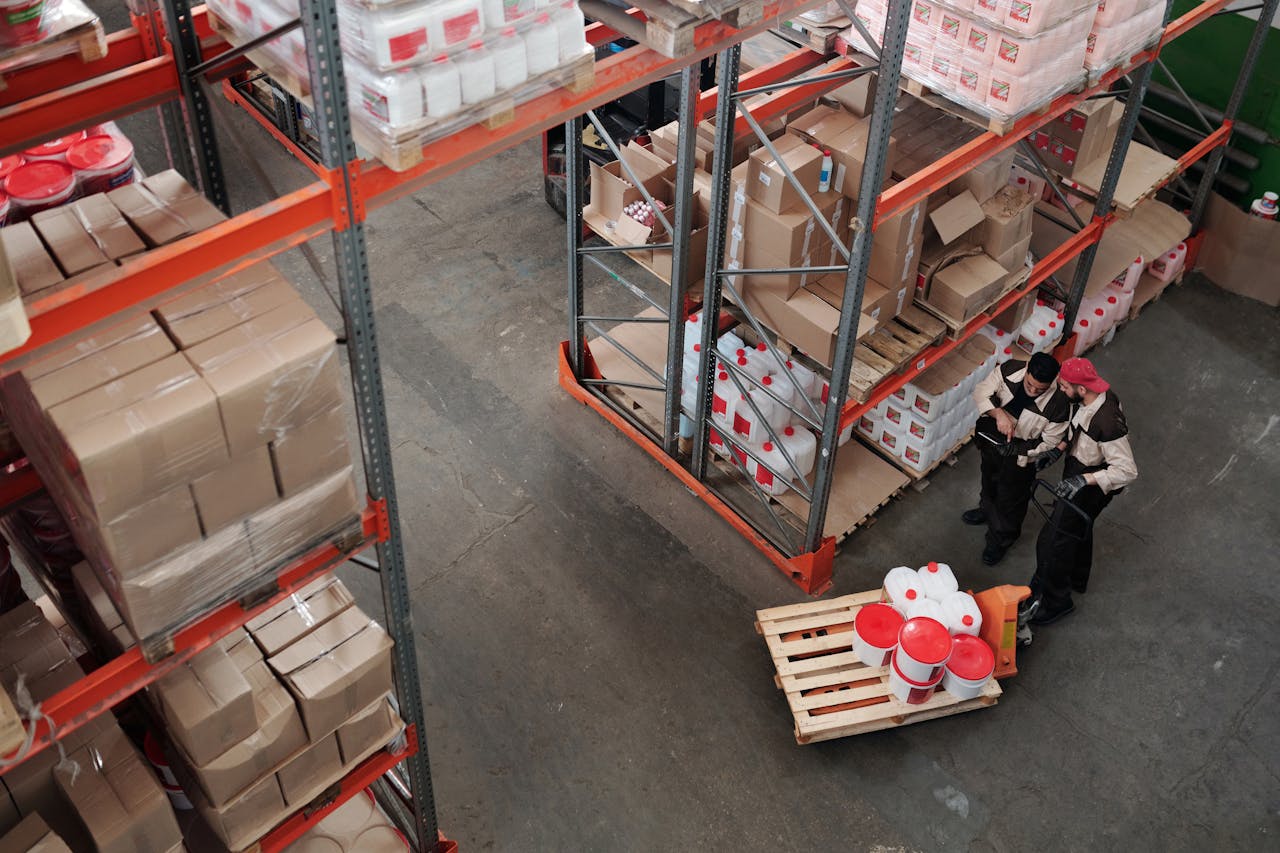 hero-img-01 Workers managing inventory on shelves in a warehouse, viewed from above.