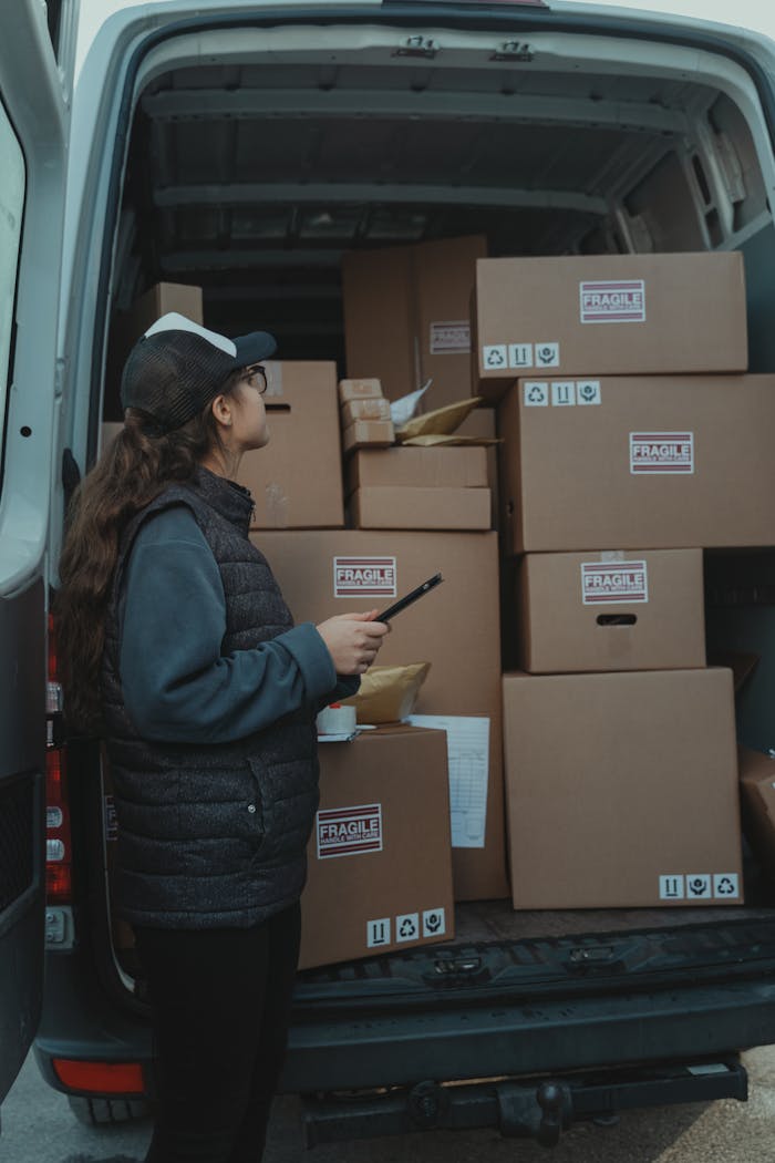 services-01 A female delivery worker organizing packages marked fragile in the back of a delivery van.